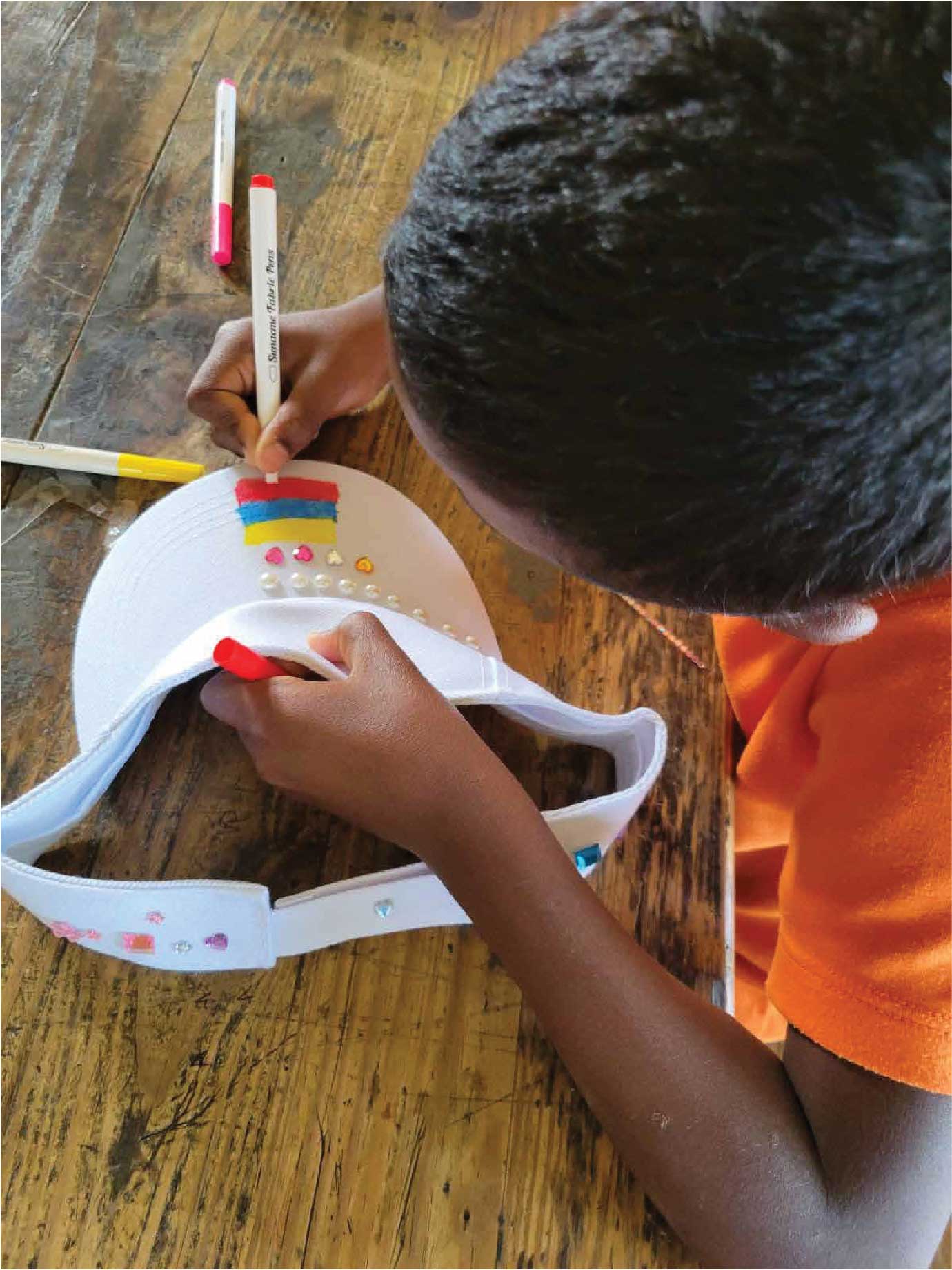Niño de la Fundación decorando una visera con marcadores